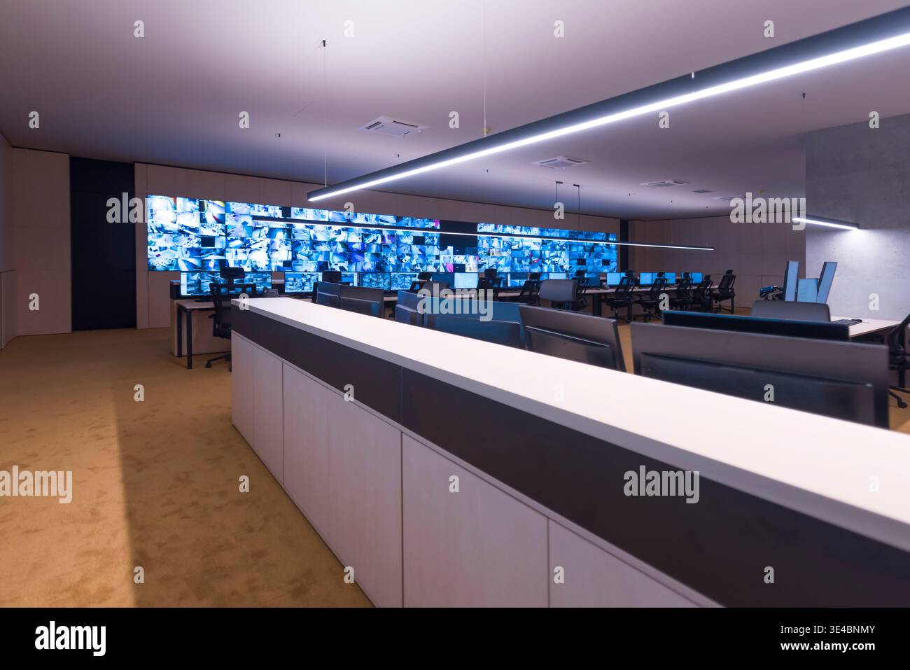 Modern security operations center with multiple workstations and large video wall displaying surveillance camera feeds. Concept of monitoring, safety, Stock Photo