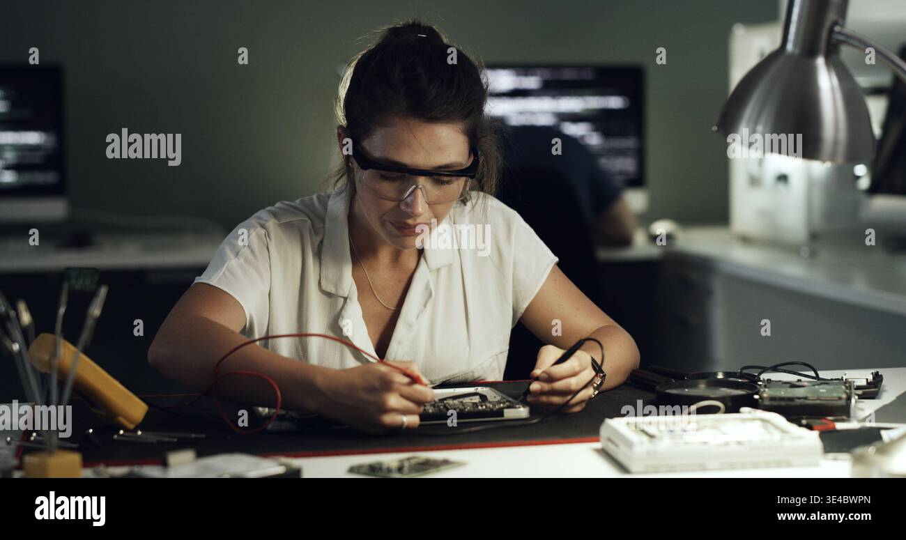Soldering, woman or circuit repair in office for hardware diagnostics, PCB maintenance or electronics. Night, technician and multimeter probe on Stock Photo