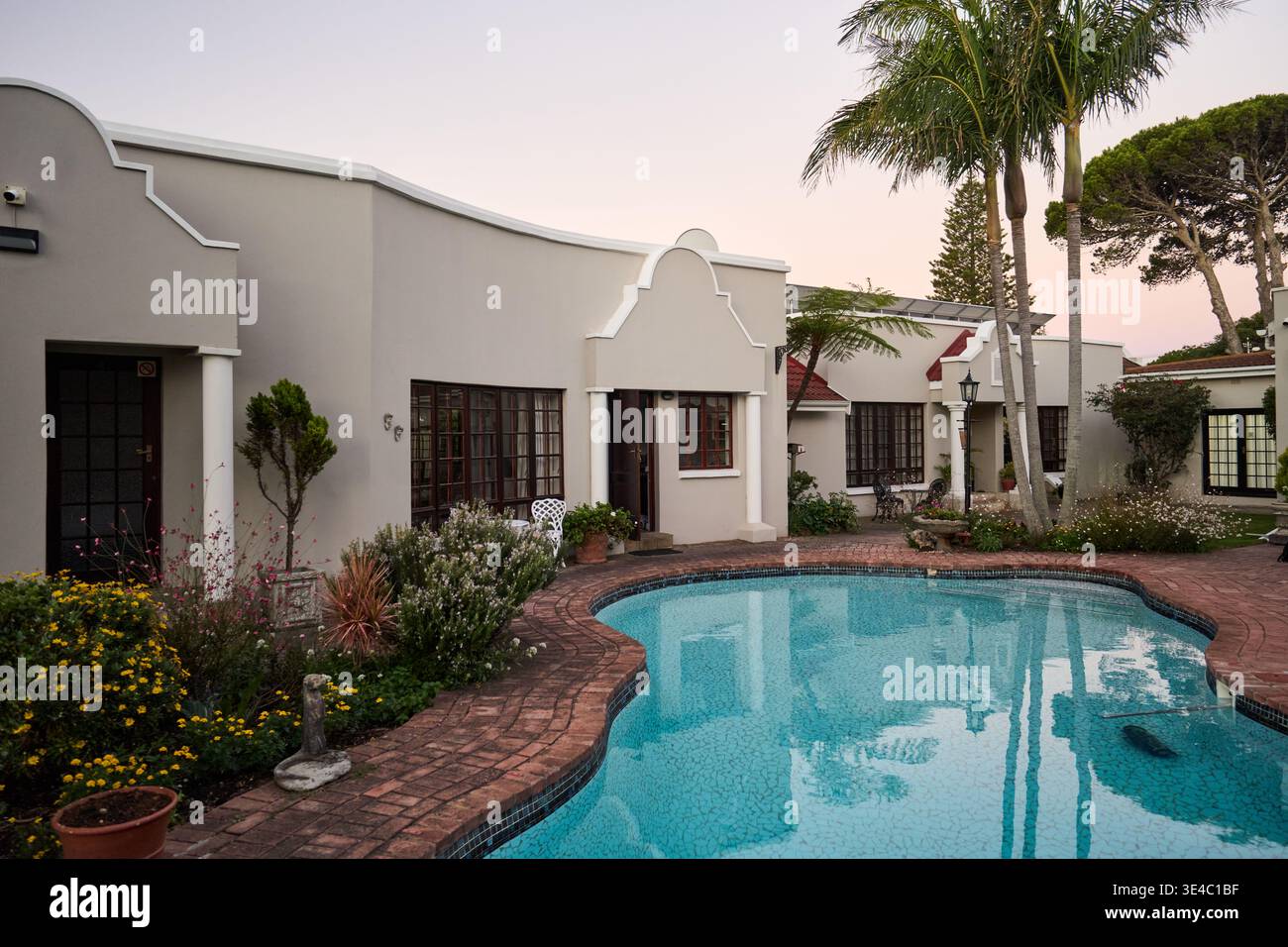 Charming House By Water At Sunset. Serene Poolside Dwelling Featuring Reflective Waters And Lush Gardens Stock Photo