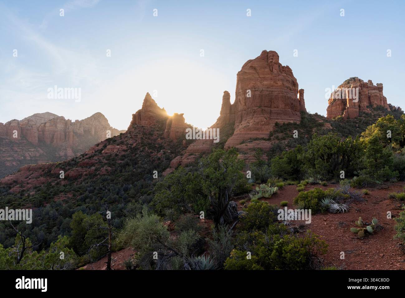 Sun setting behind red rock formations Stock Photo