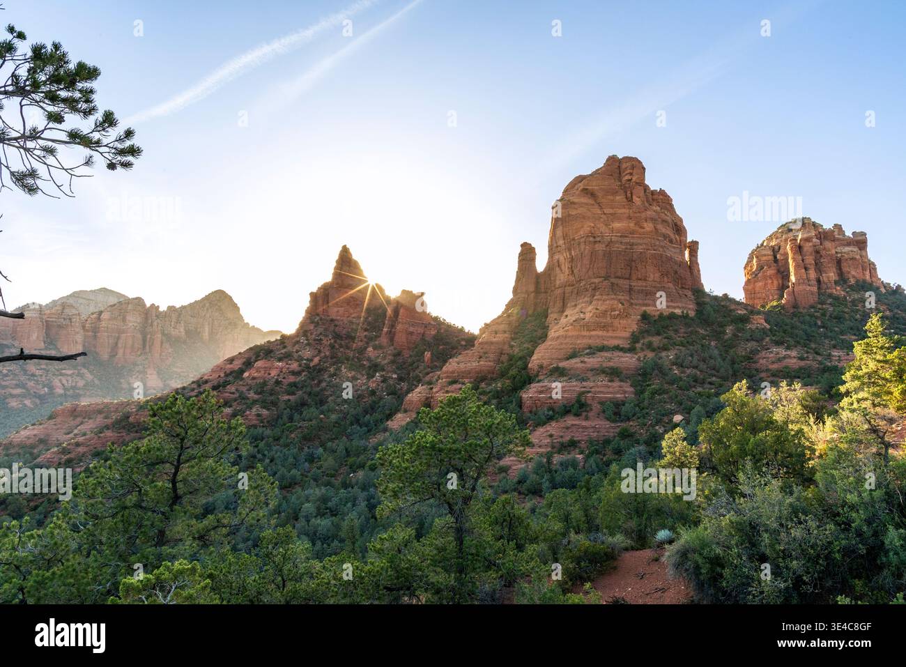 Starburst sun setting behind rock formations landscape Stock Photo
