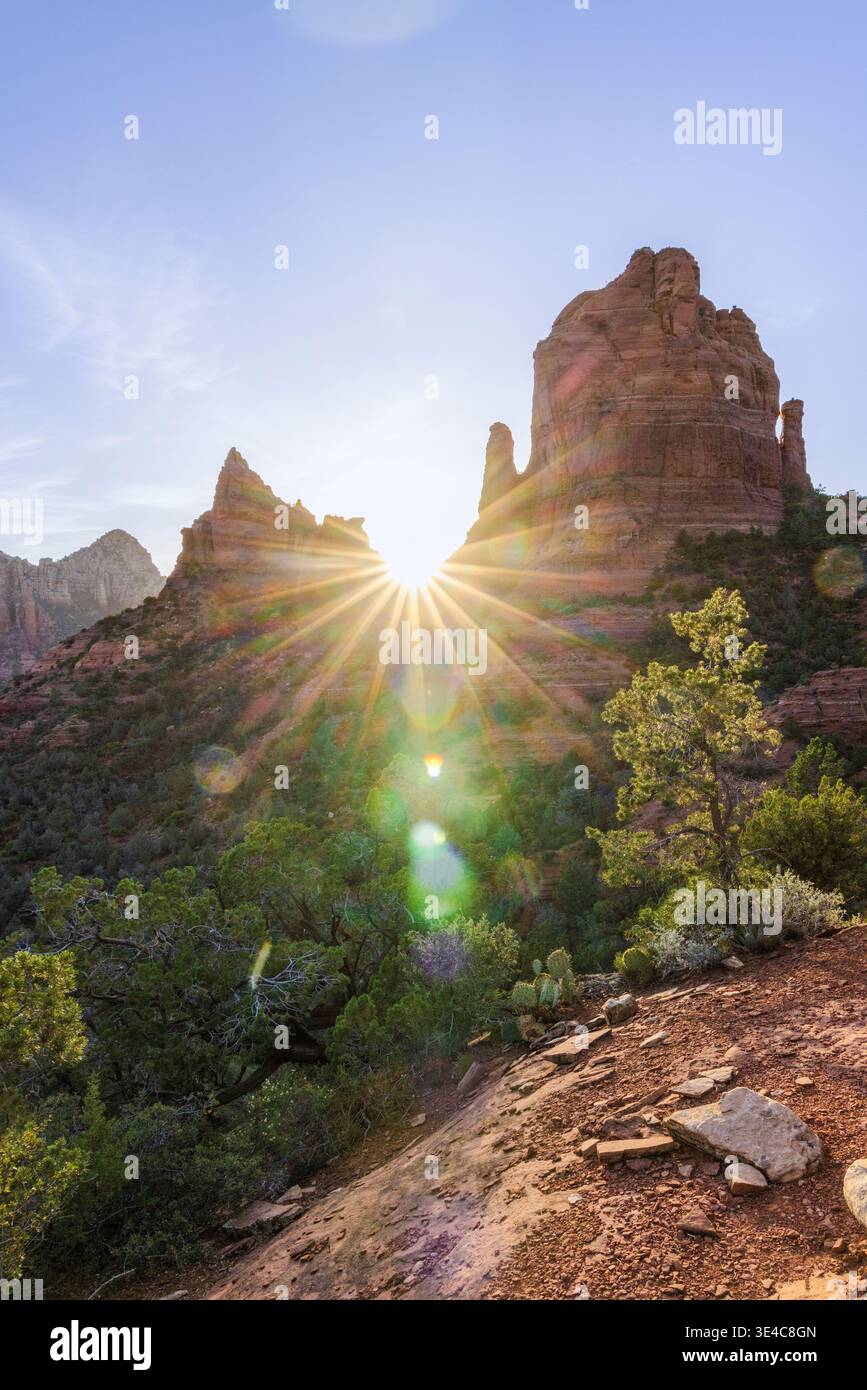 Sunburst flare sun setting behind red rock formations Stock Photo