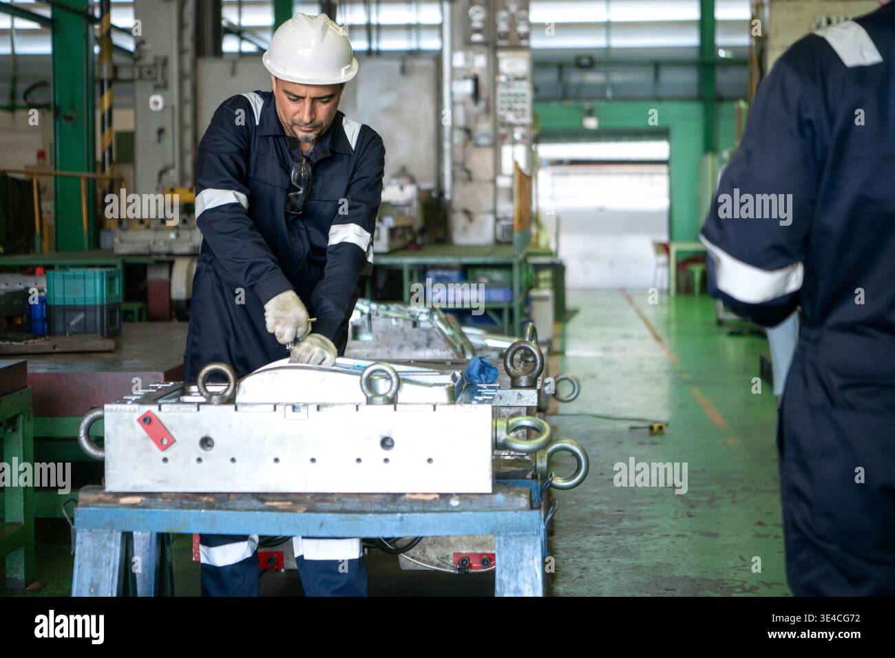Industrial engineers and technicians discussing machine operation while inspecting equipment in a manufacturing factory || Model released Stock Photo