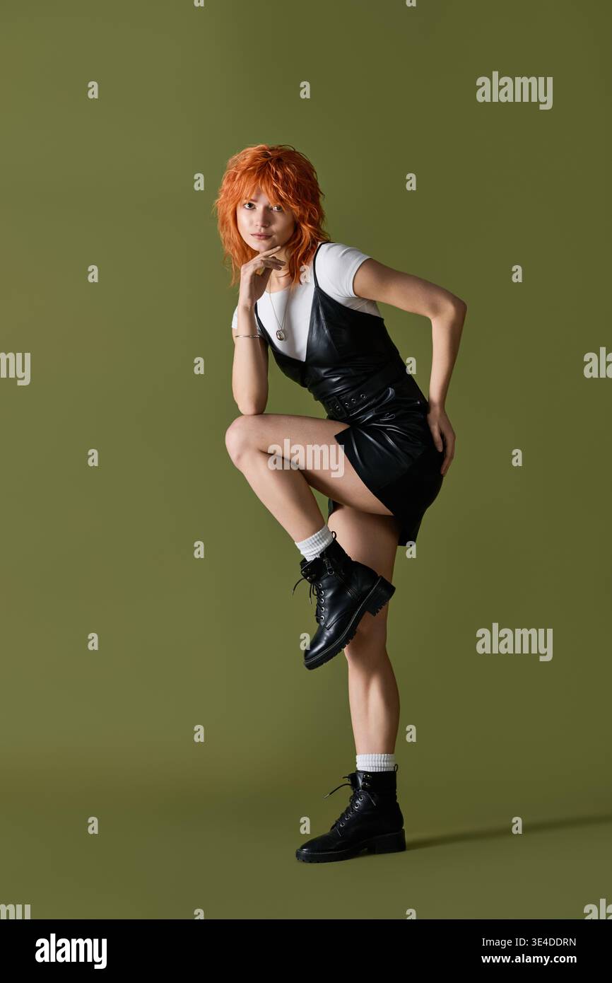 Red haired woman showcases a stylish outfit against a vibrant green spring backdrop. Stock Photo
