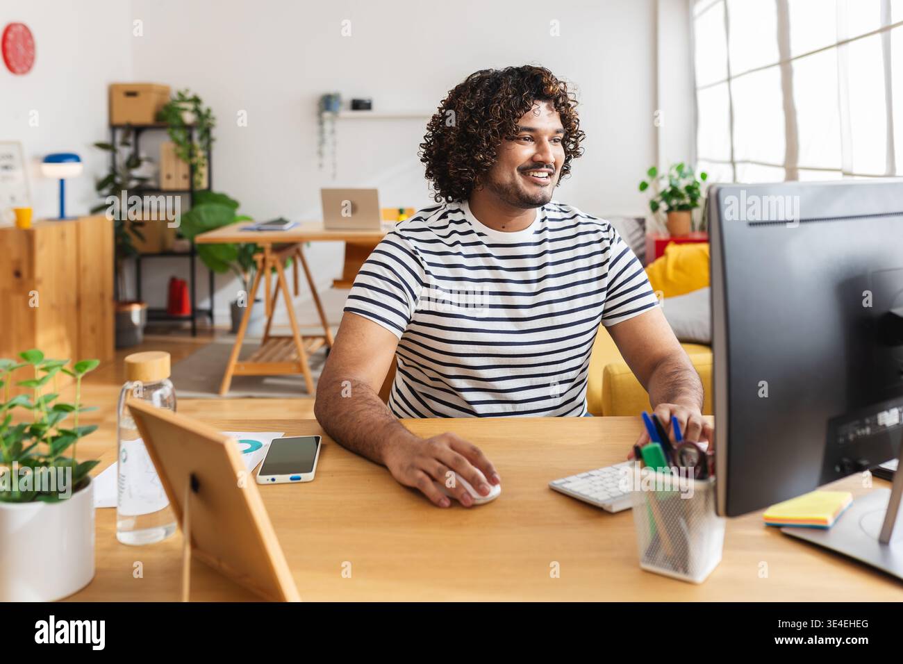 Young Indian man using computer in modern home office Stock Photo