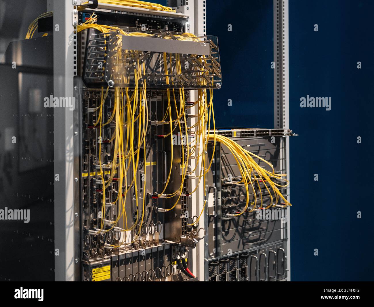 Two server racks with bright yellow cables. Data center's core network switch with numerous computers and routers - data center modular architecture. Stock Photo