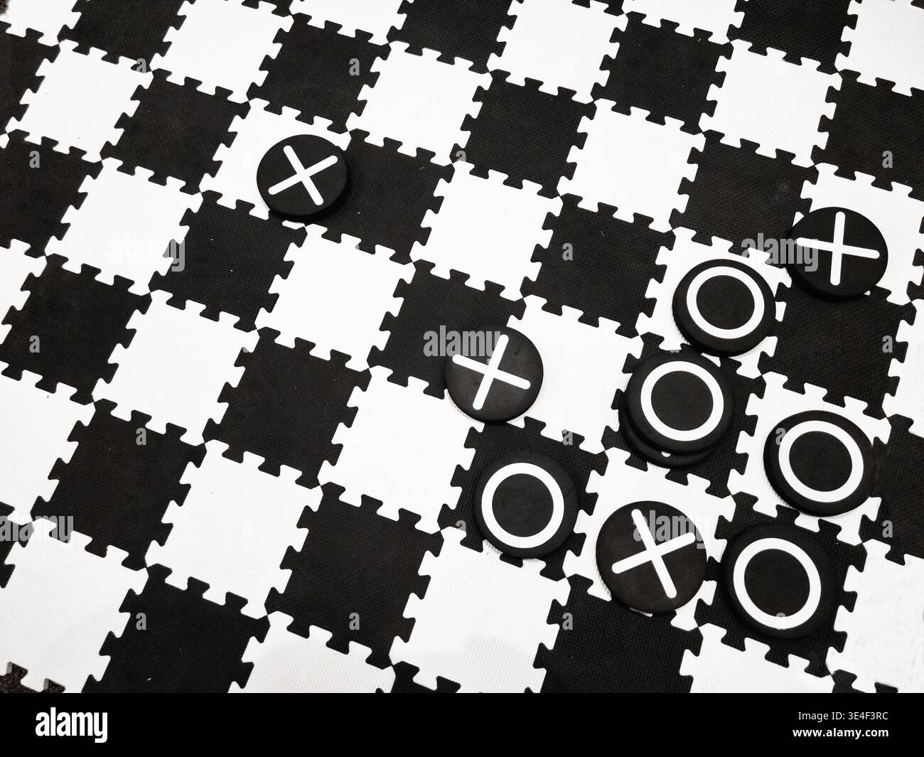 A black and white checkerboard with Xs and Os is put together as a floor game. Stock Photo