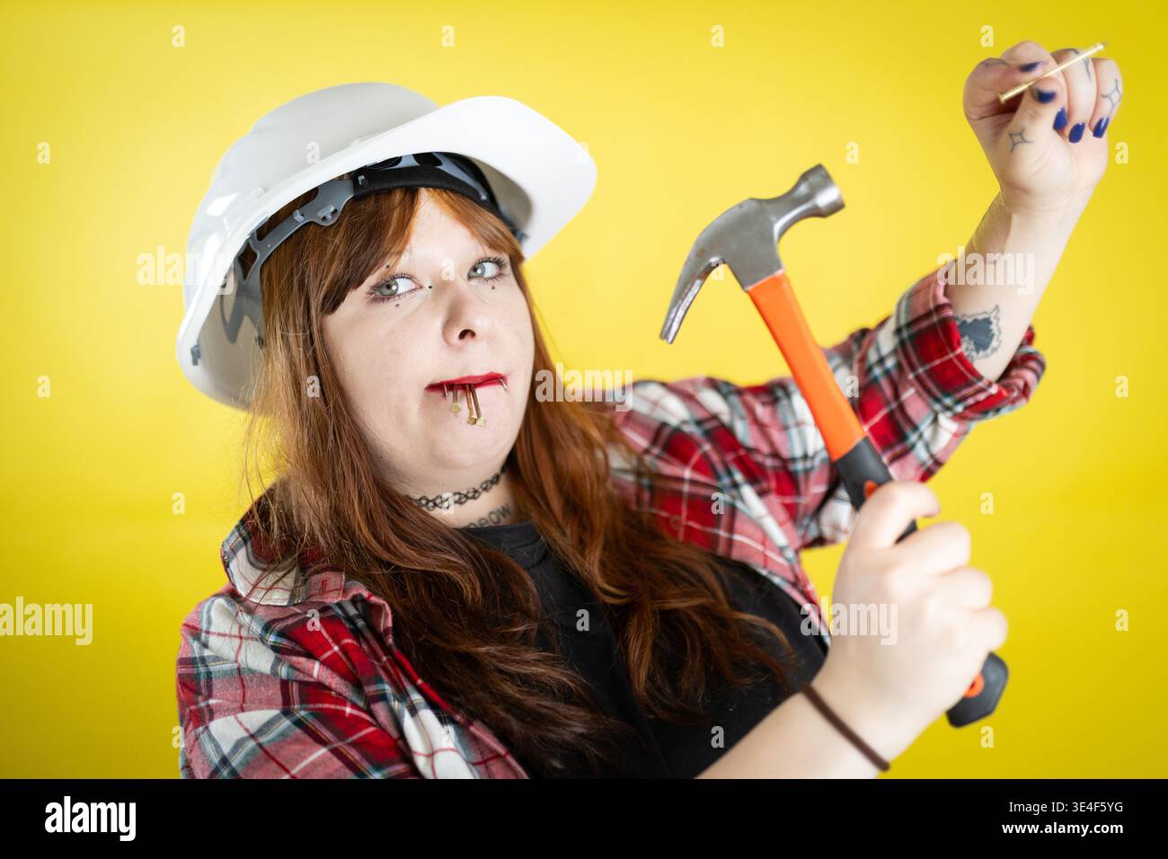 Woman wearing hard hat holding hammer ready for construction Stock Photo