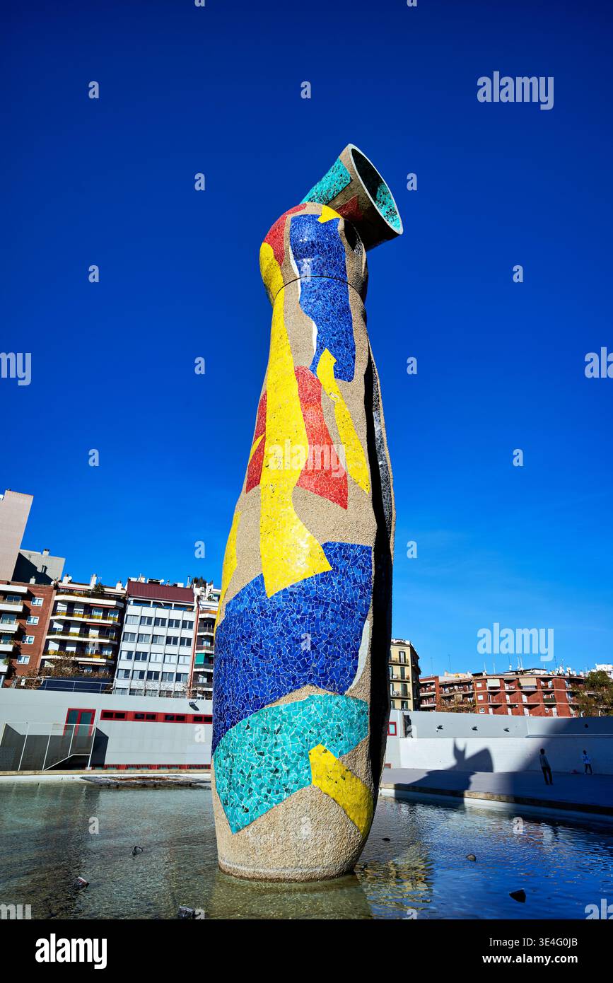 The sculpture 'Dona i Ocell' stands tall in Parc de l'Escorxador in Barcelona. Visitors view its colorful design against a clear blue sky. Stock Photo