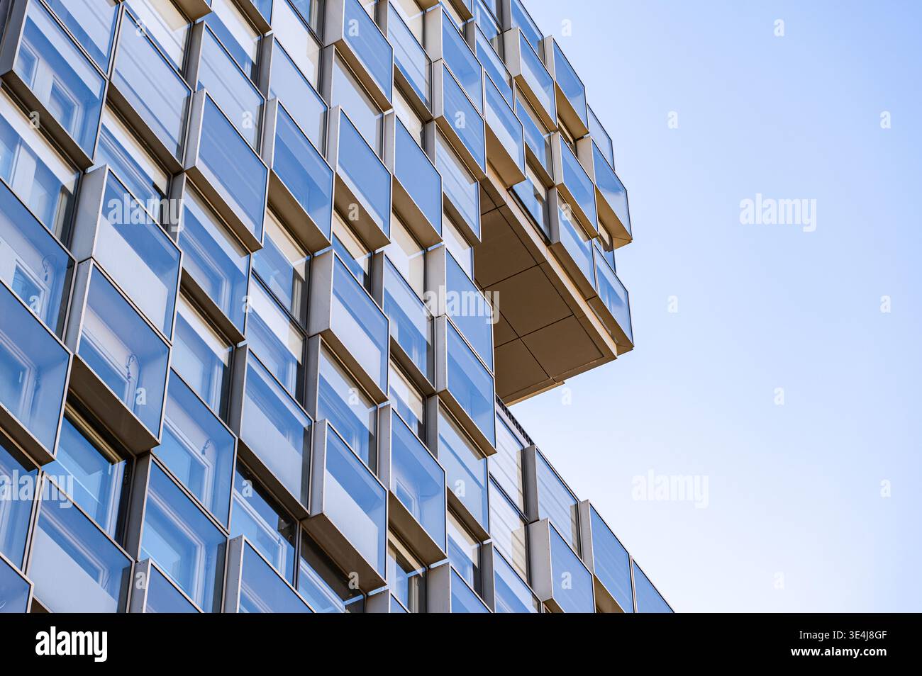 Close-up view of a modern glass building facade, featuring repeating geometric window panels and clean lines, showing contemporary architecture detail Stock Photo