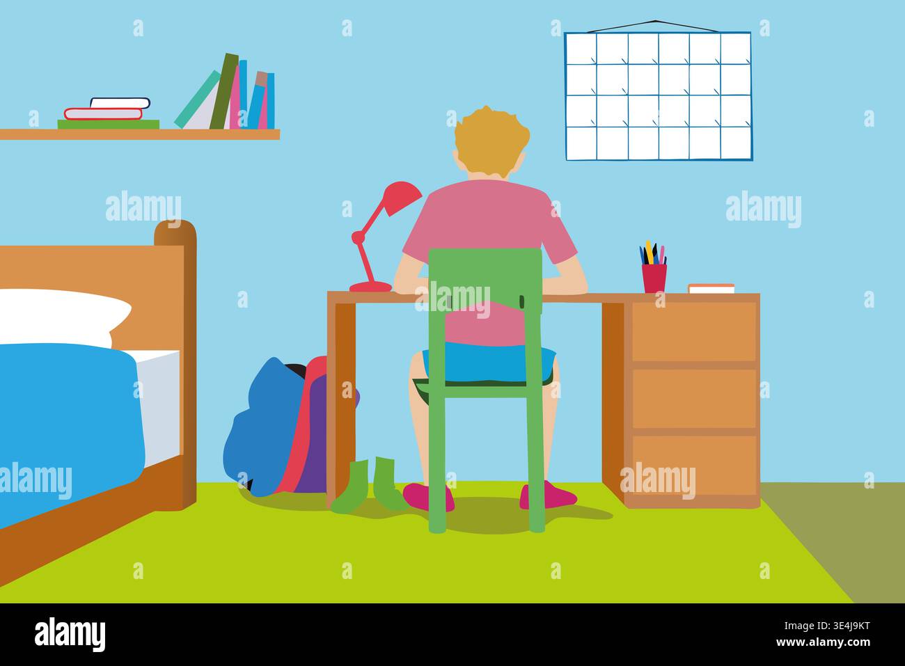 A boy sits at a desk in his bedroom with his back to the viewer. He is working on a task with a lamp on the desk. Books and a calendar are placed on t Stock Photo
