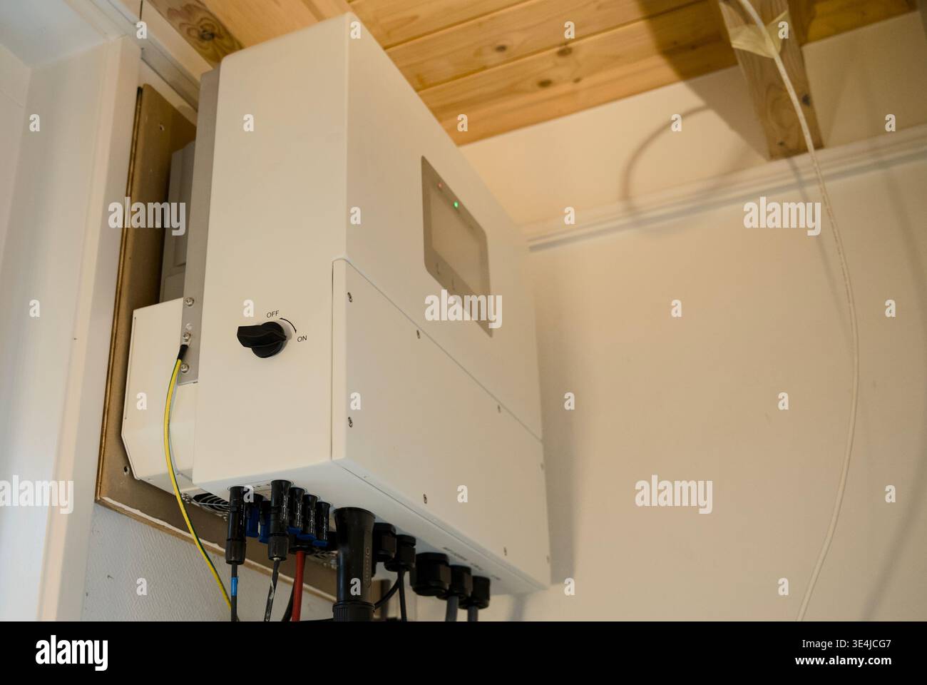 Residential solar inverter wall mounted with DC cables and on/off switch, renewable energy home installation Stock Photo