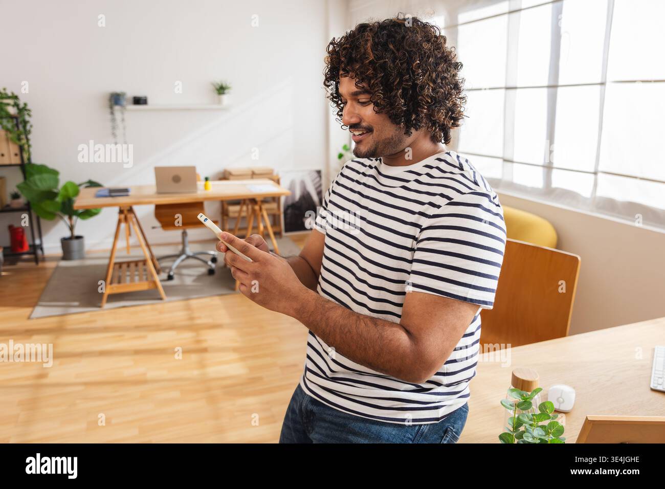Young Indian man using smartphone while standing Stock Photo