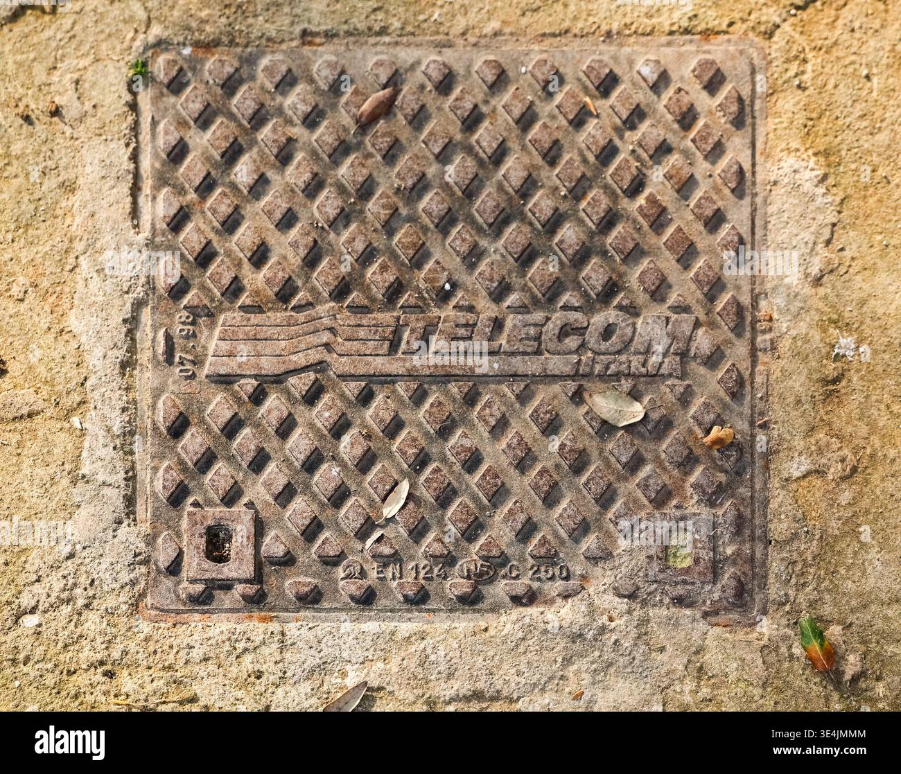 Naples, Italy - 5. March 2026: TELECOM ITALIA utility access cover on the ground showing rust and grid pattern Stock Photo
