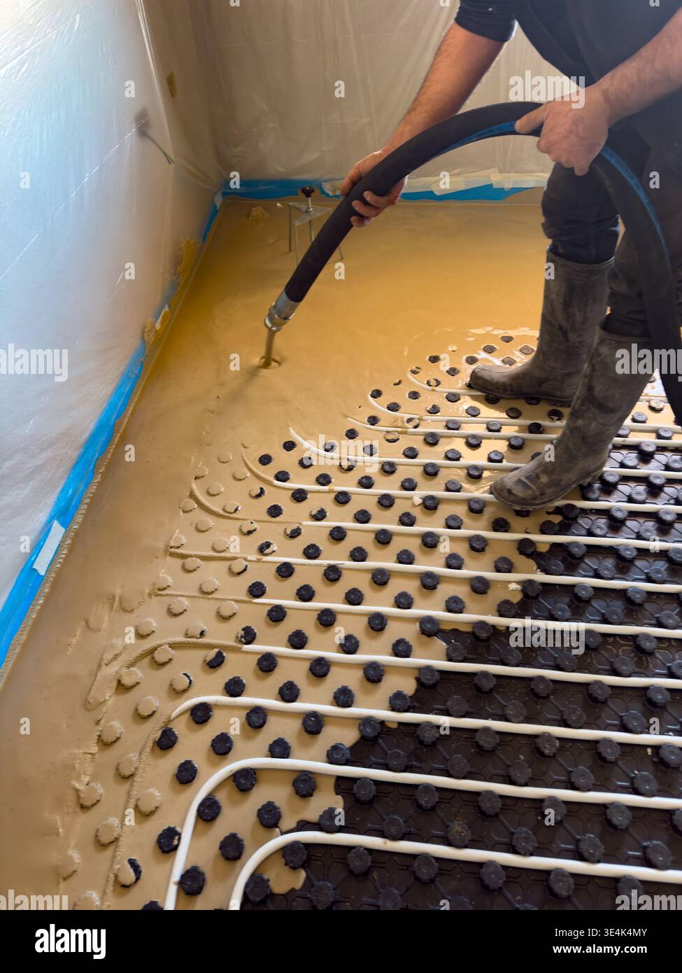 Construction worker installing radiant floor heating with liquid screed Stock Photo