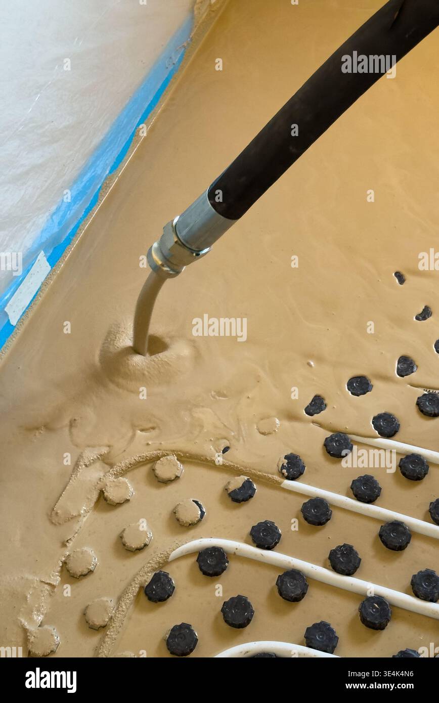 Construction worker installing radiant floor heating with liquid screed Stock Photo
