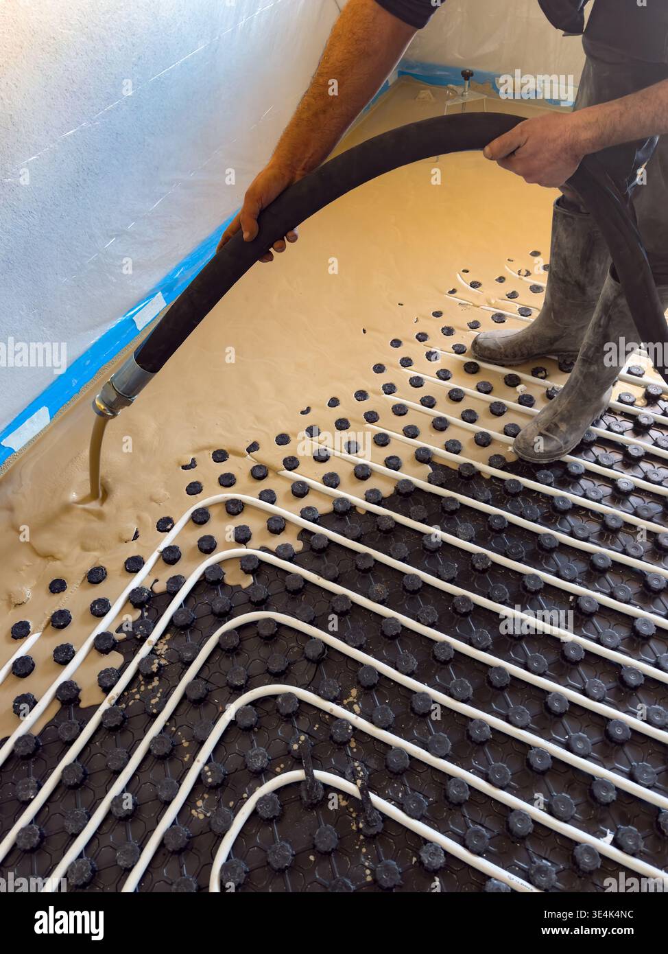 Construction worker installing radiant floor heating with liquid screed Stock Photo
