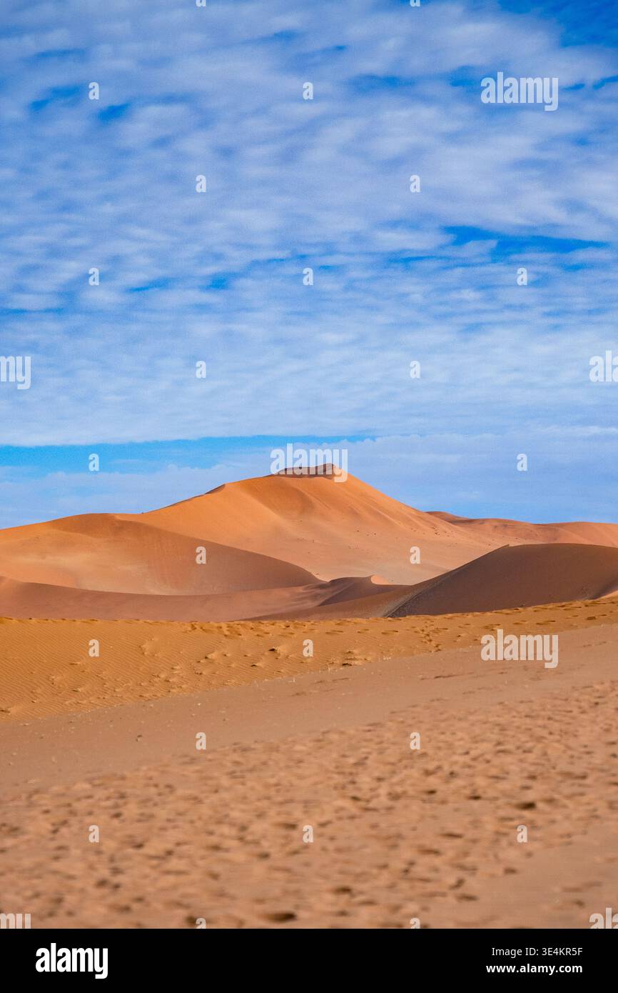 Sinuous Sand Dunes Under Patterned Cloud Sky, Crest And Rippled Slopes Catching Warm Light, Expansive Minimal Stock Photo