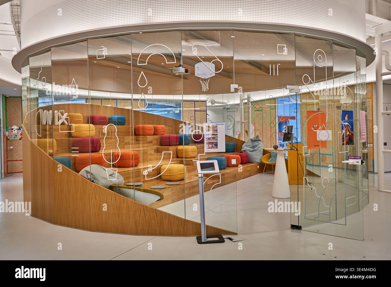 Interior view of a modern, circular conference room enclosed by curved floor-to-ceiling glass walls decorated with white abstract line graphics Stock Photo