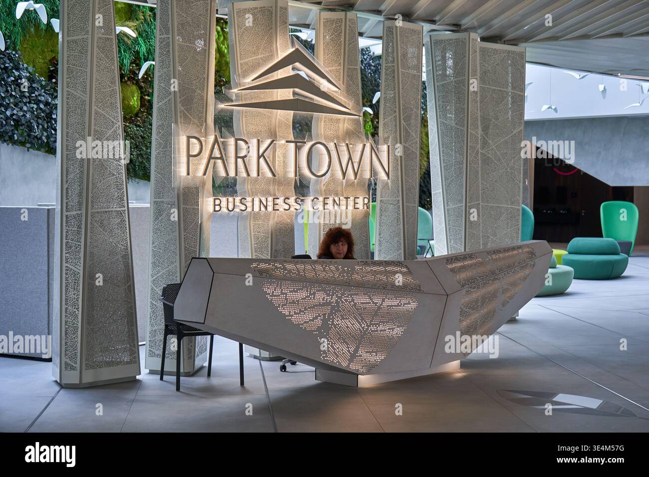 Modern reception area of Parktown Business Center featuring an angular geometric reception desk with perforated backlit metal panels displaying Stock Photo