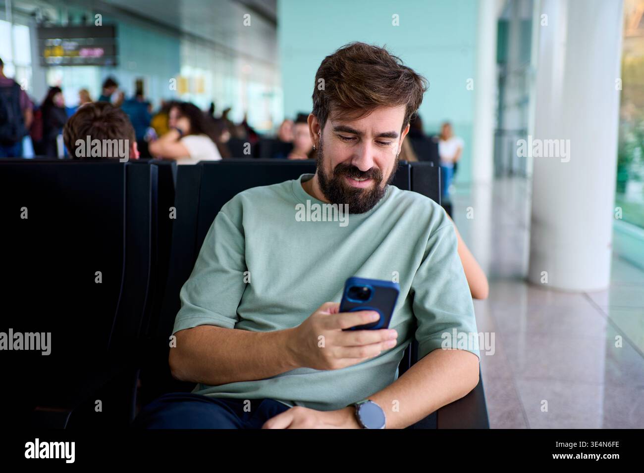 Smiling man using smartphone at airport gate Stock Photo