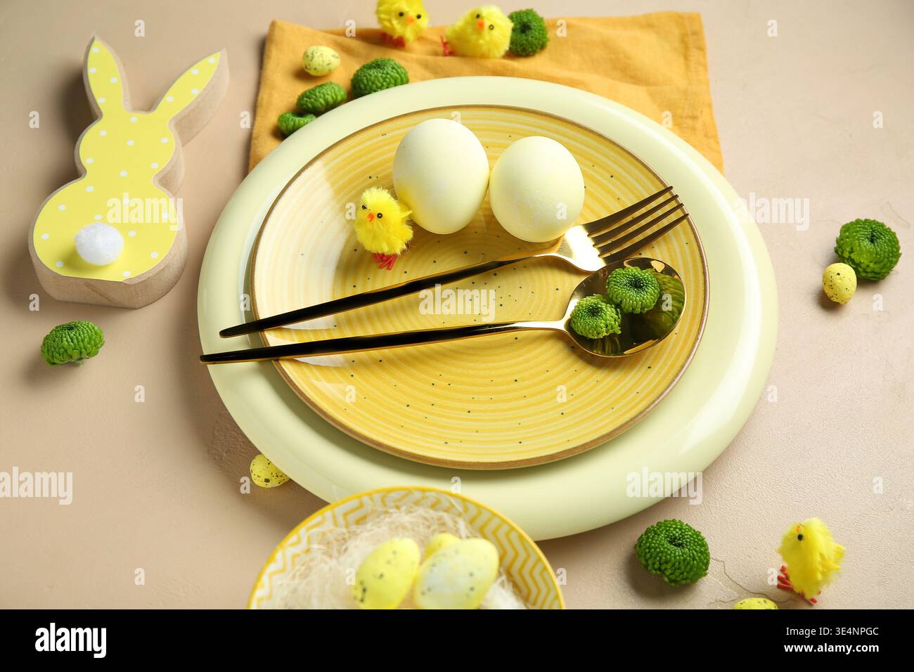Stylish table setting for Easter celebration with flowers on beige background Stock Photo