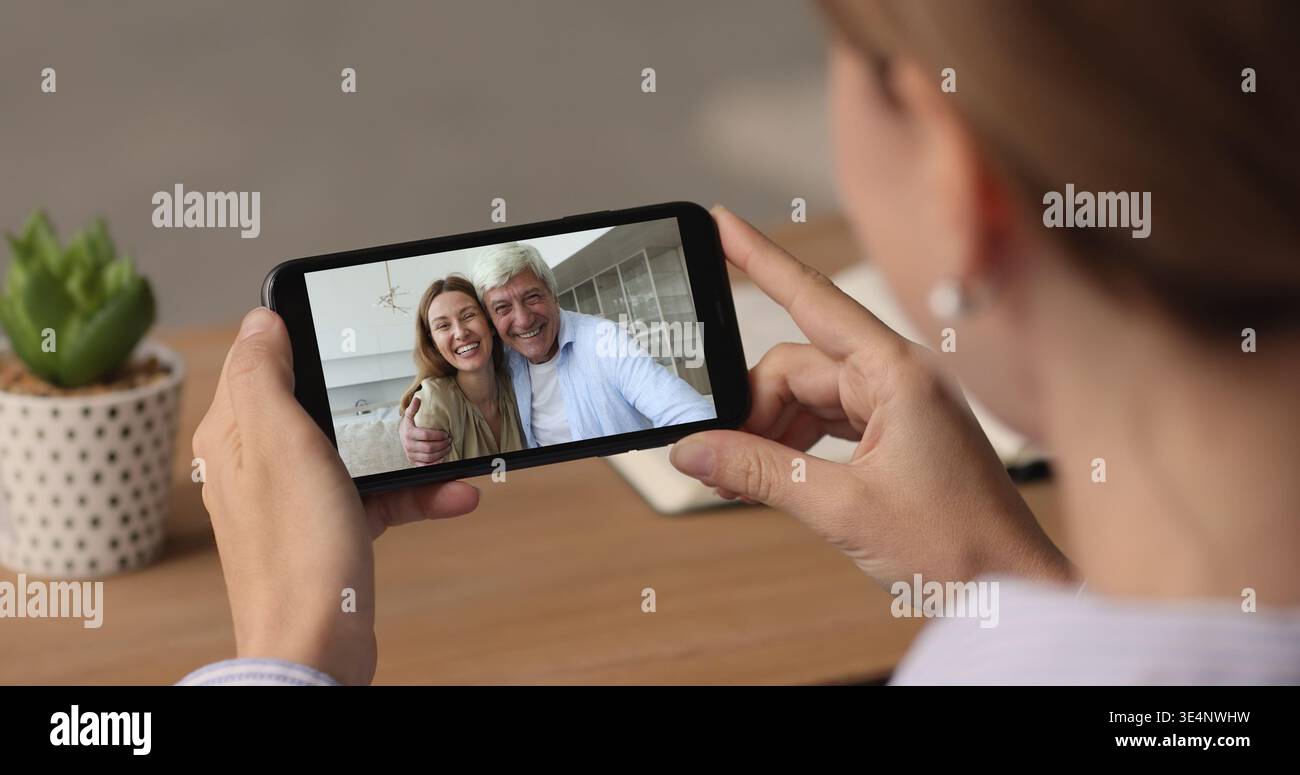 Female hold smartphone engaged in virtual meeting with family Stock Photo