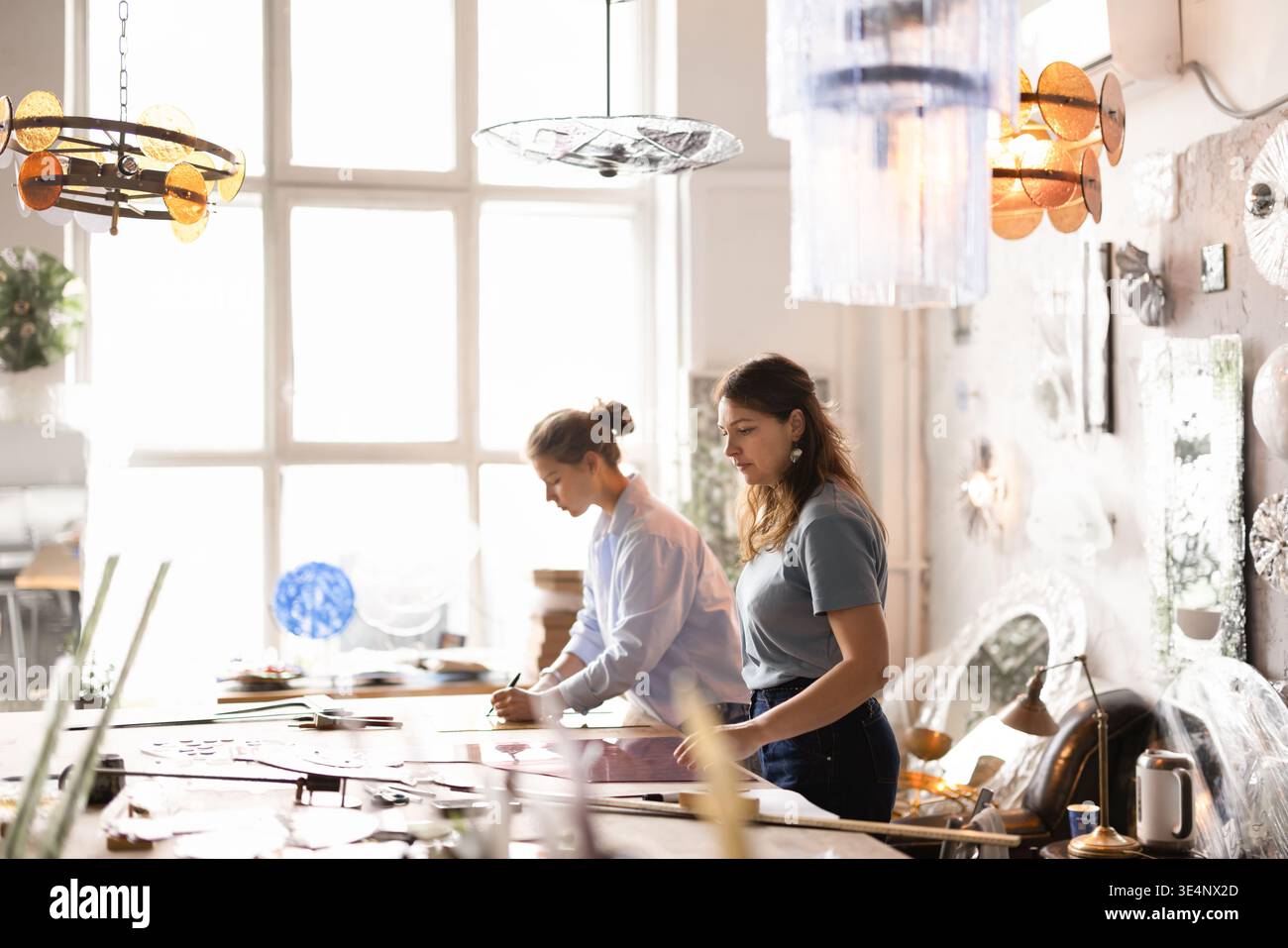 Two female artisans working on glasswork project in workshop studio Stock Photo