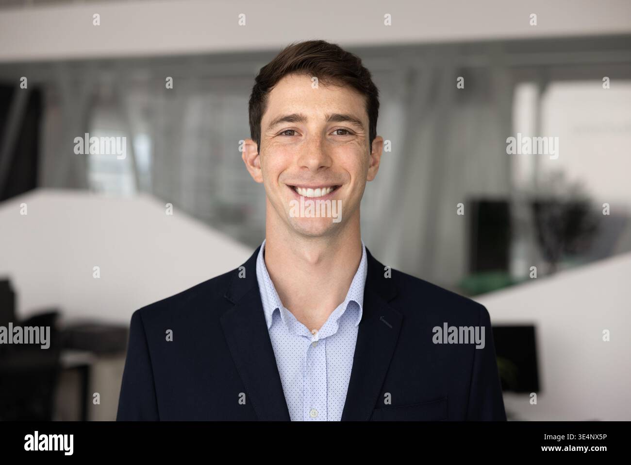 Headshot portrait of young businessman standing confidently in contemporary office Stock Photo