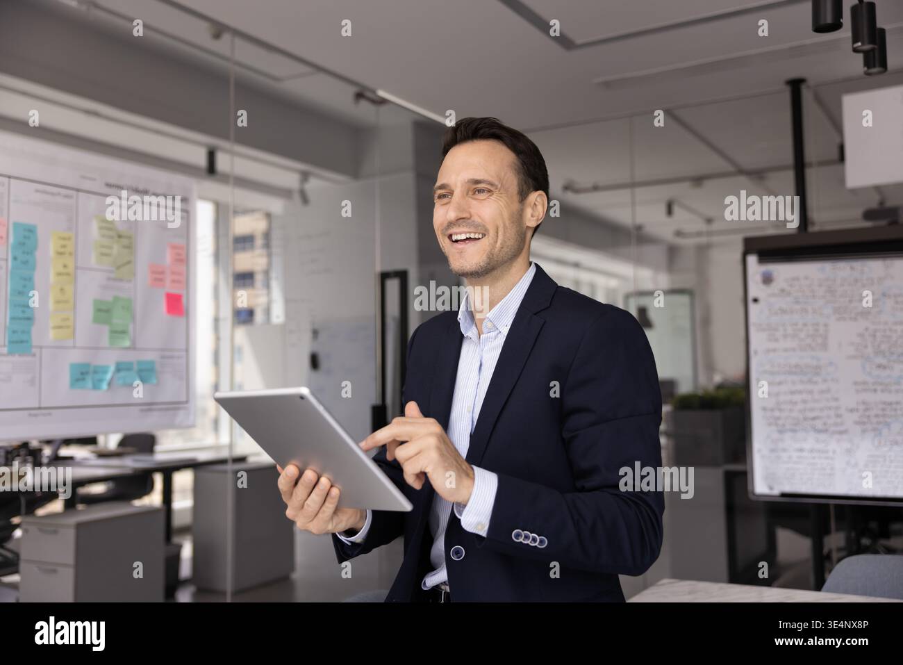 Motivated businessman looking forward with smile distracted from using pad Stock Photo