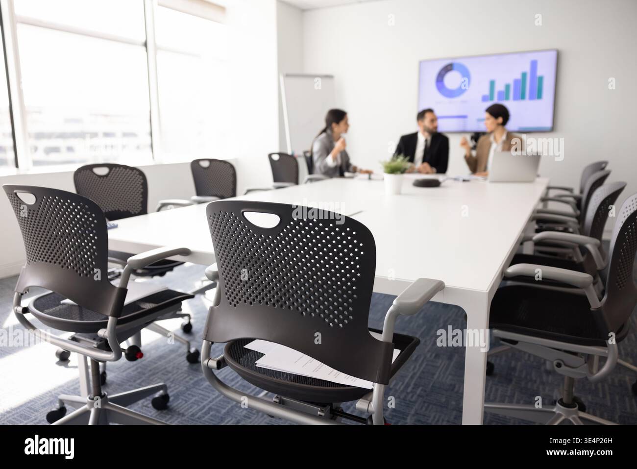Businesspeople sit around conference table, discussing strategy, analyzing data Stock Photo