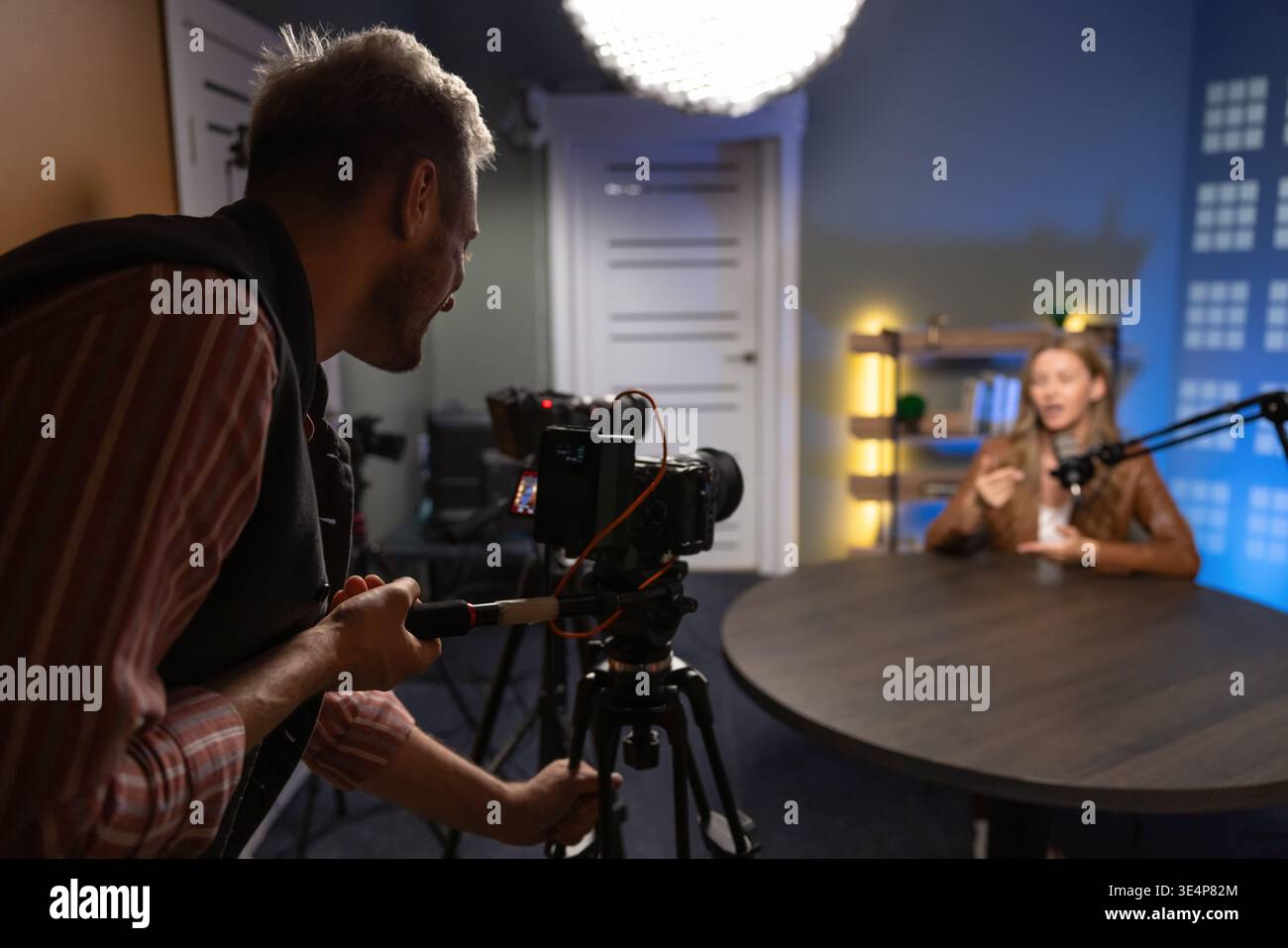 Videographer recording female guest during podcast interview in professional studio Stock Photo