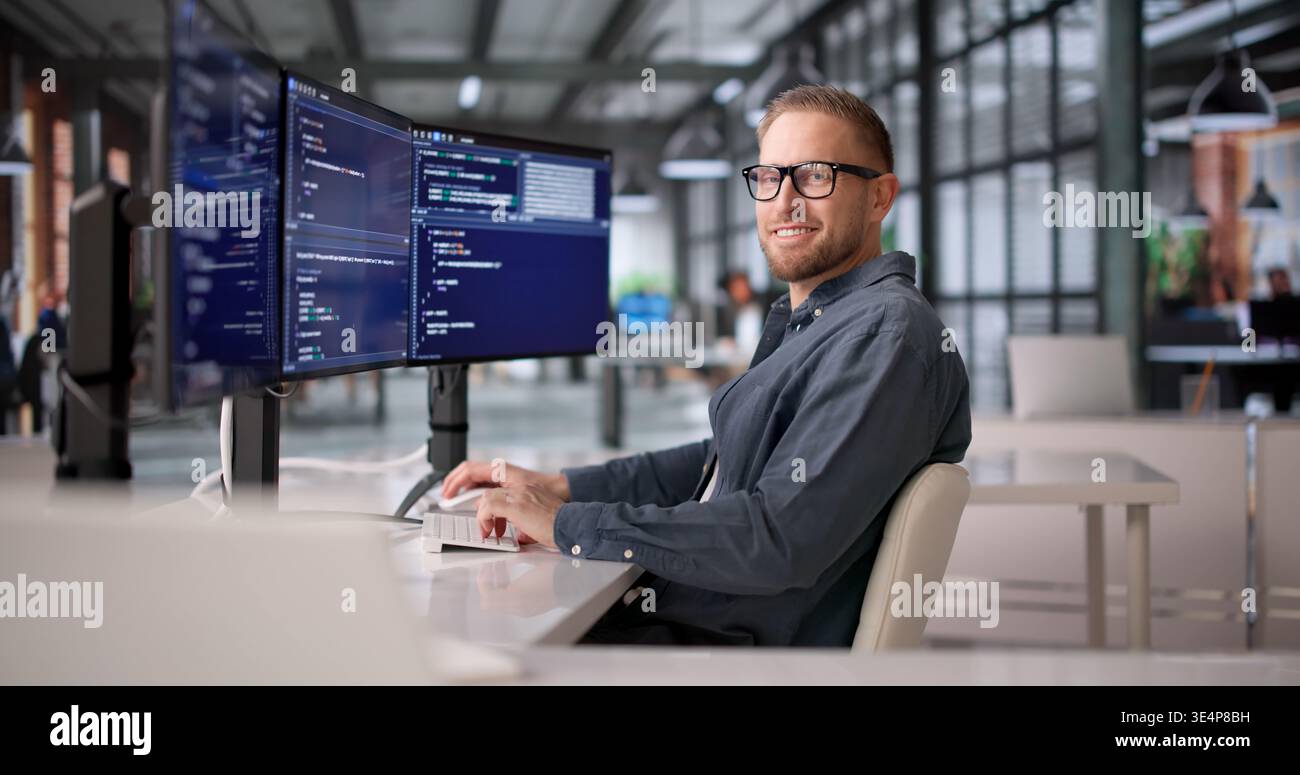 Joyful Software Developer Coding With Several Screens In Office Setting Stock Photo