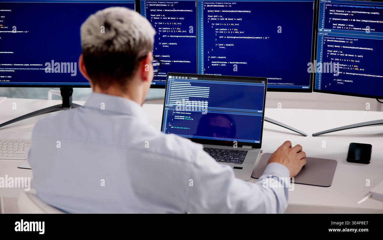 Hispanic Male Software Developer Working On Coding And Tech Solutions At Office Desk Stock Photo