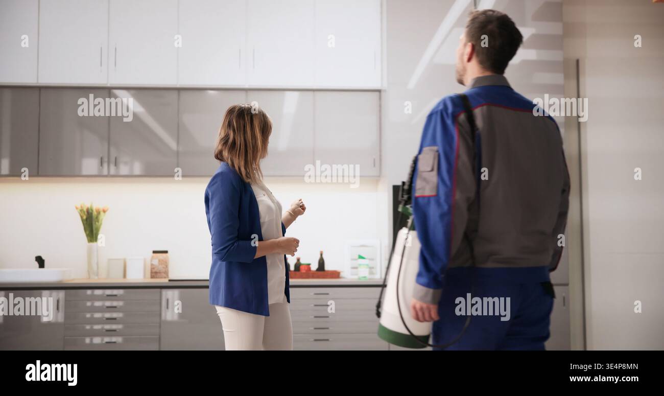 Homeowner Points Out Pest Issues In Kitchen To Exterminator For Treatment Stock Photo