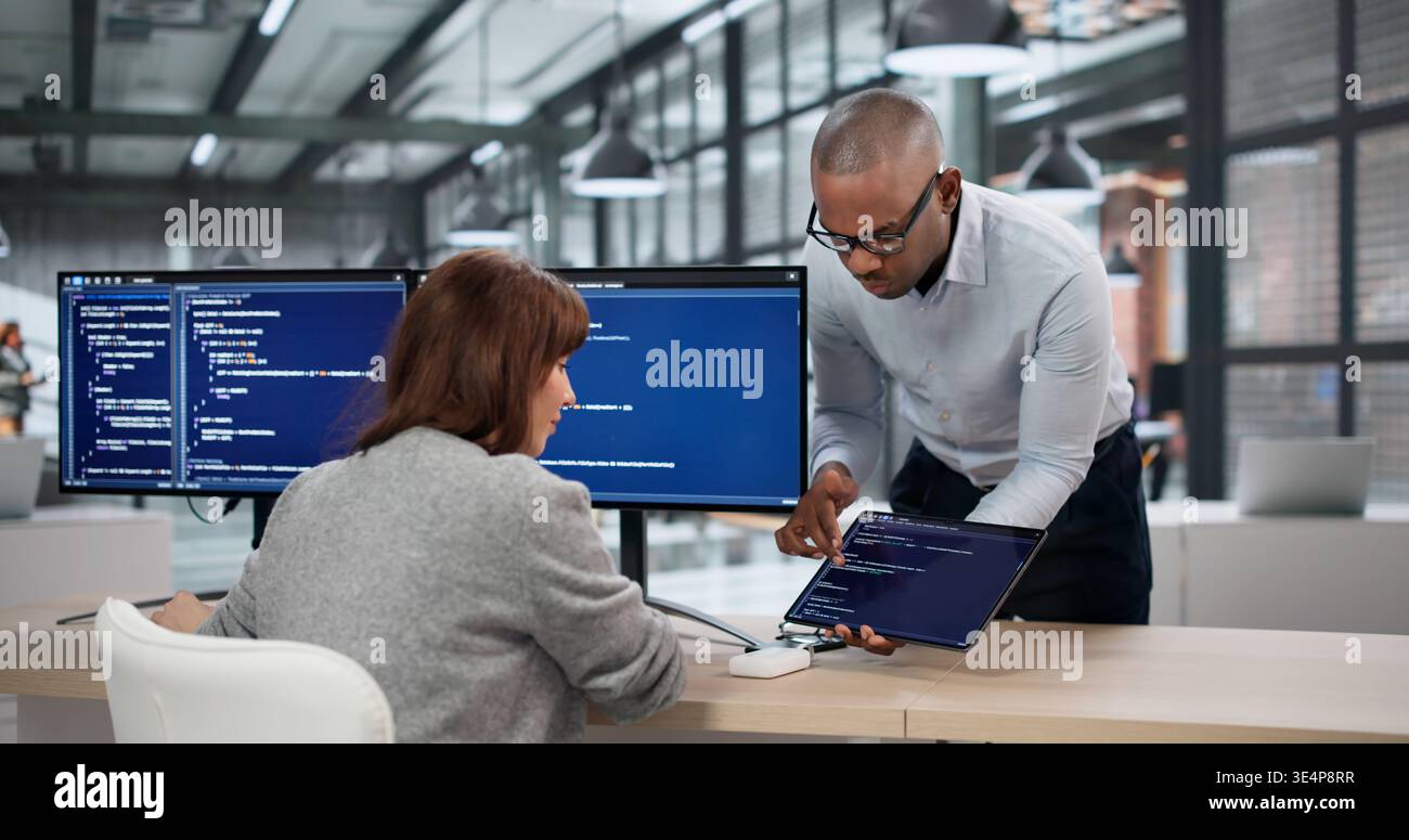 Two Software Developers Coding On Computers As An Accountant Reviews Billing Data Nearby; A Female Engineer Stock Photo