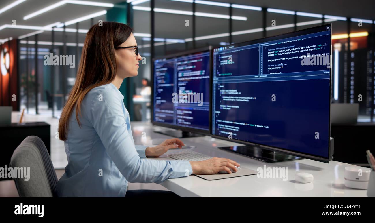 Female Software Engineer Deeply Engaged In Coding On Desktop Computer Stock Photo