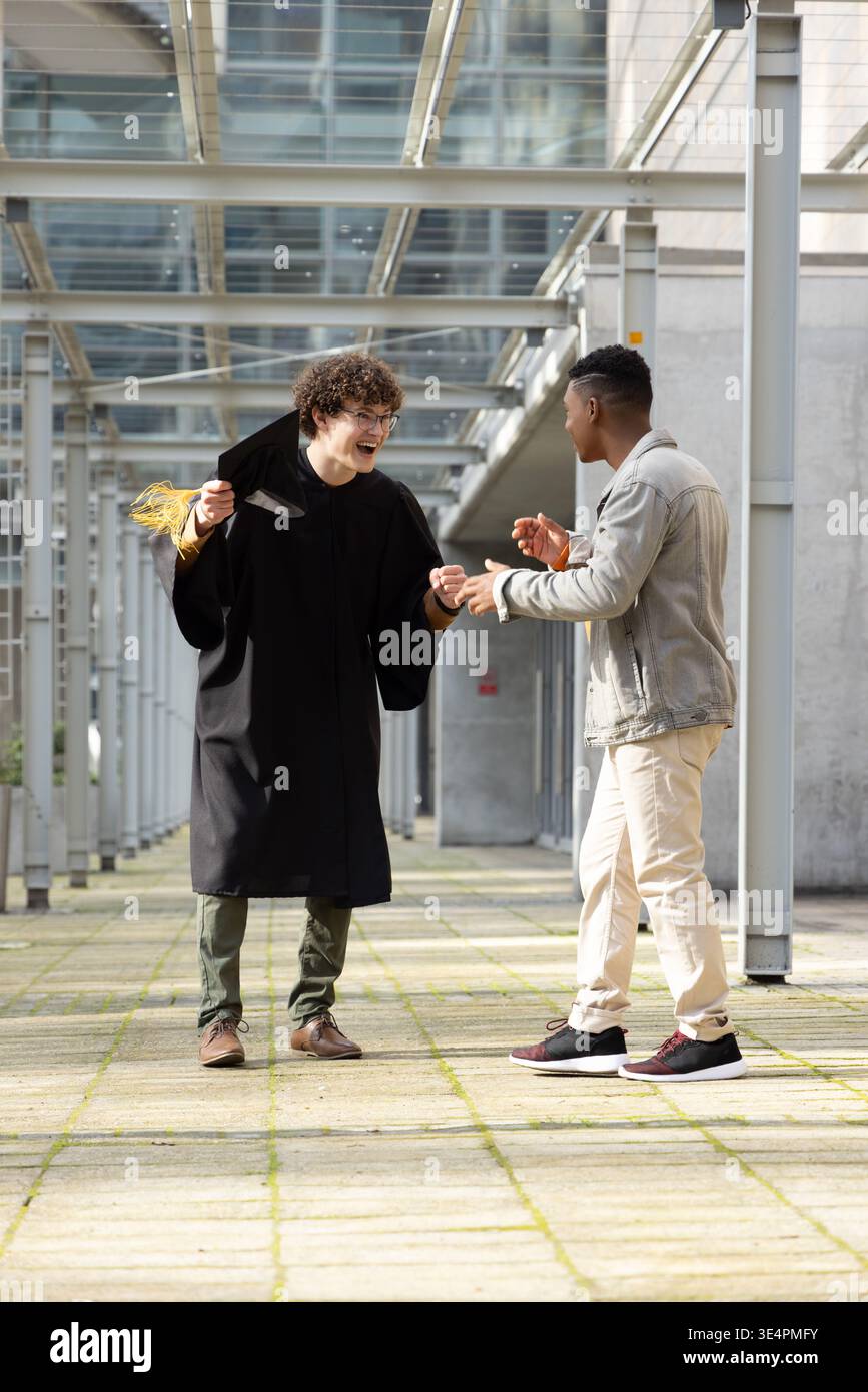 Diverse male pals chatting under glass roof in corridor, one wearing ...