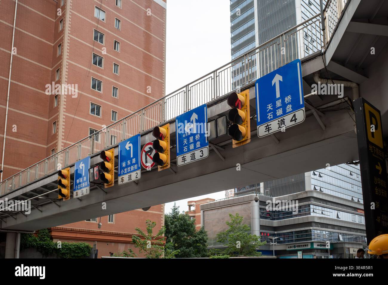 Urban overpass with traffic signals and directional signs. Buildings ...