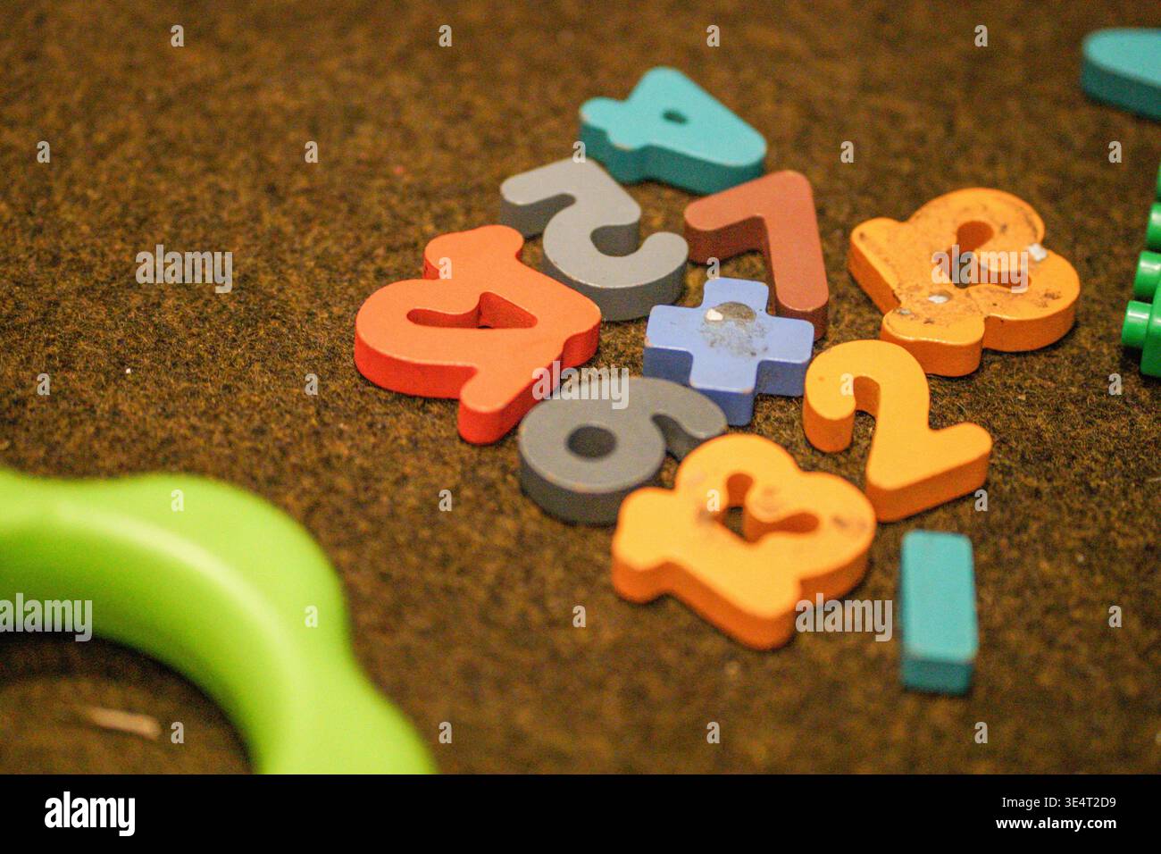 Colorful wooden numbers scattered on a textured surface, educational toy for children learning counting and math. Stock Photo