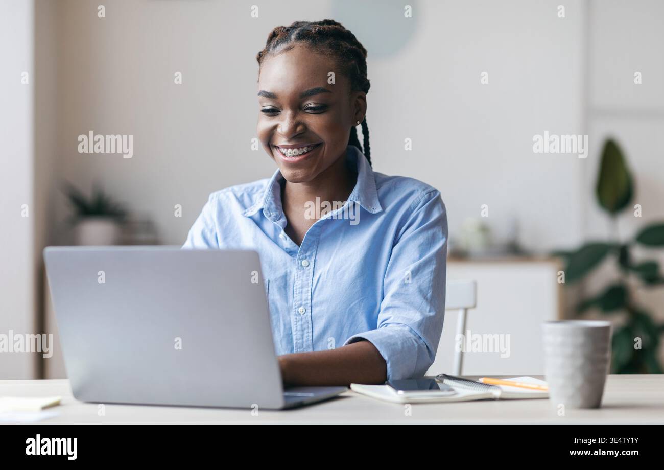 Young Black Secretary Working On Laptop In Modern Office, Typing On Keyboard Stock Photo
