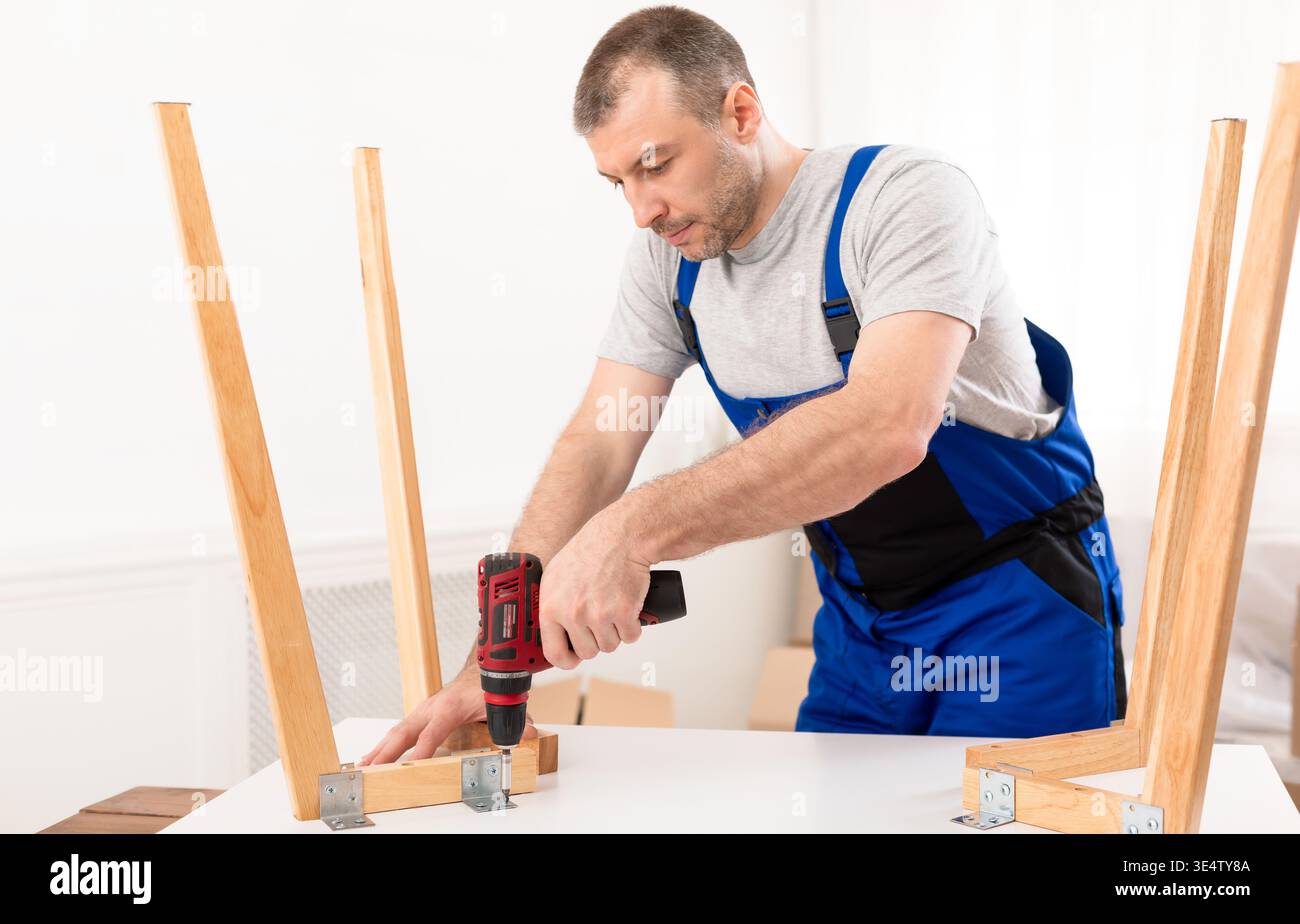 Man Carpenter Using Electric Drill Assembling Wooden Table Stock Photo