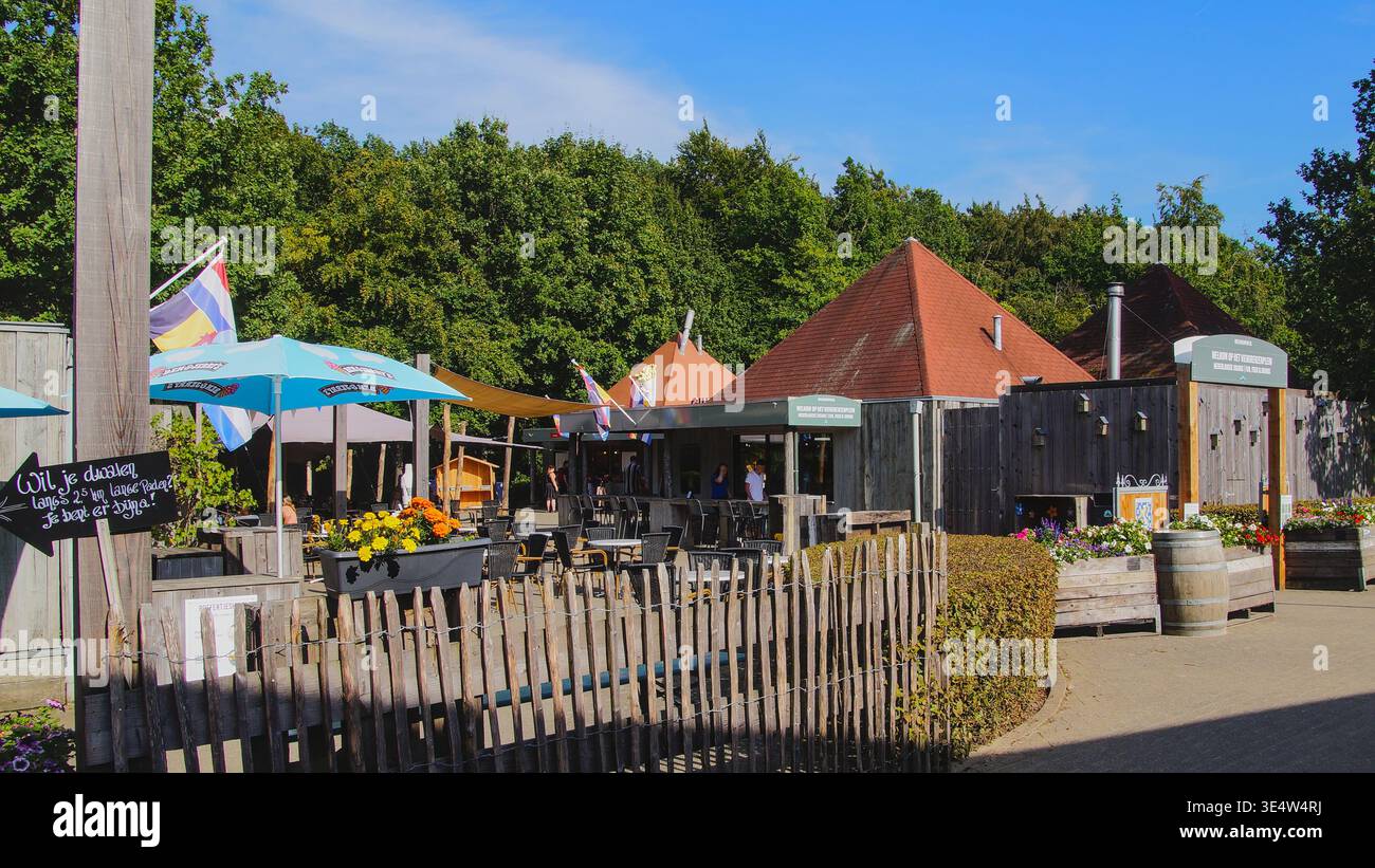 Cozy beer garden with sun umbrellas and wooden elements, surrounded by nature in a relaxed outdoor setting. Stock Photo