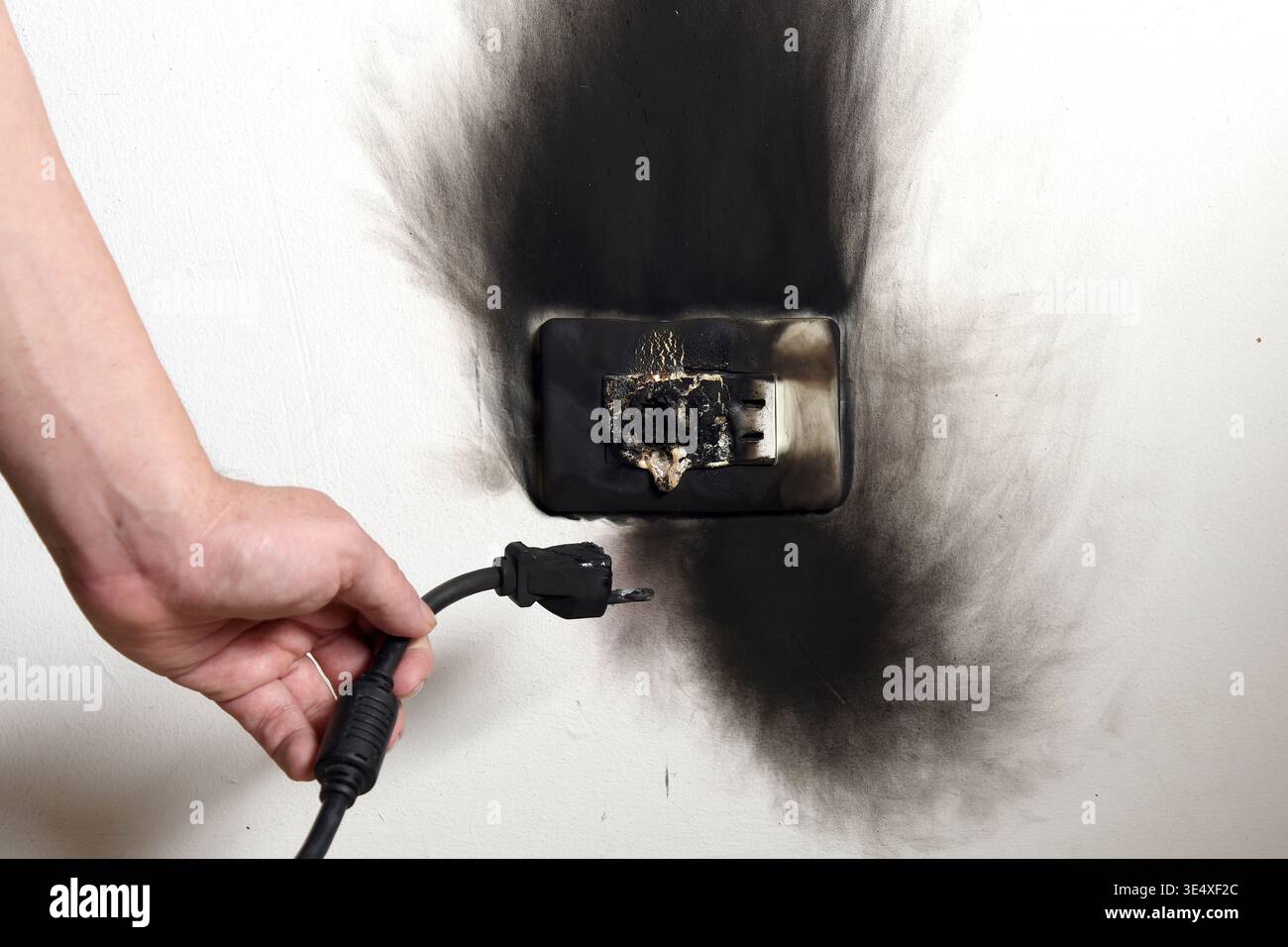 Hand with burnt cable. Isolated electrical fault in the plug. Fire hazard. Stock Photo