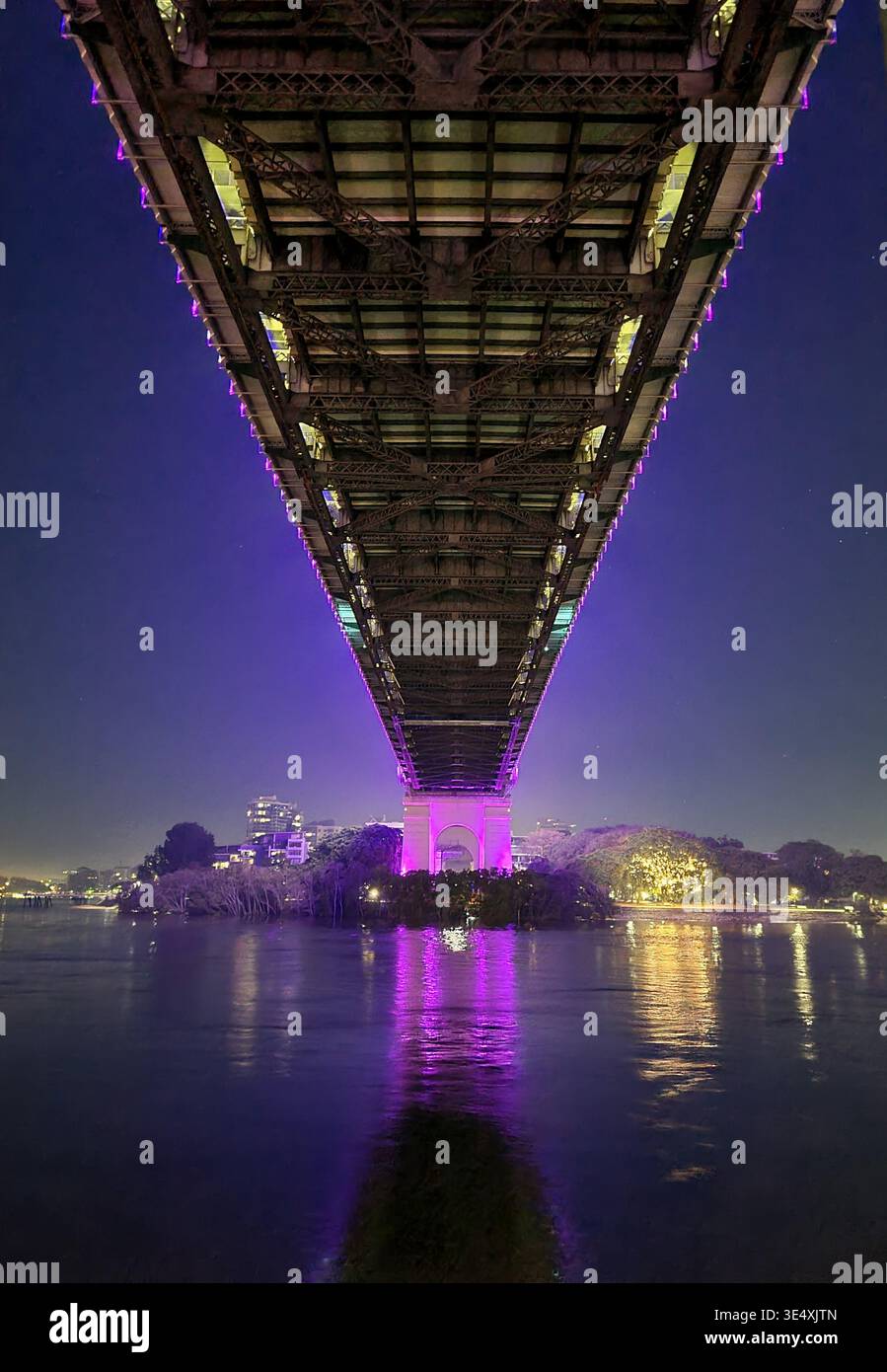 Underneath the Story Bridge at night with vibrant purple architectural lighting reflecting on the Brisbane River, Queensland, Australia. - Smartphone Captured Stock Image