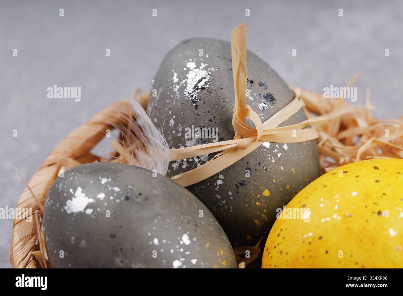 Close up Easter eggs with feathers in wicker basket Stock Photo