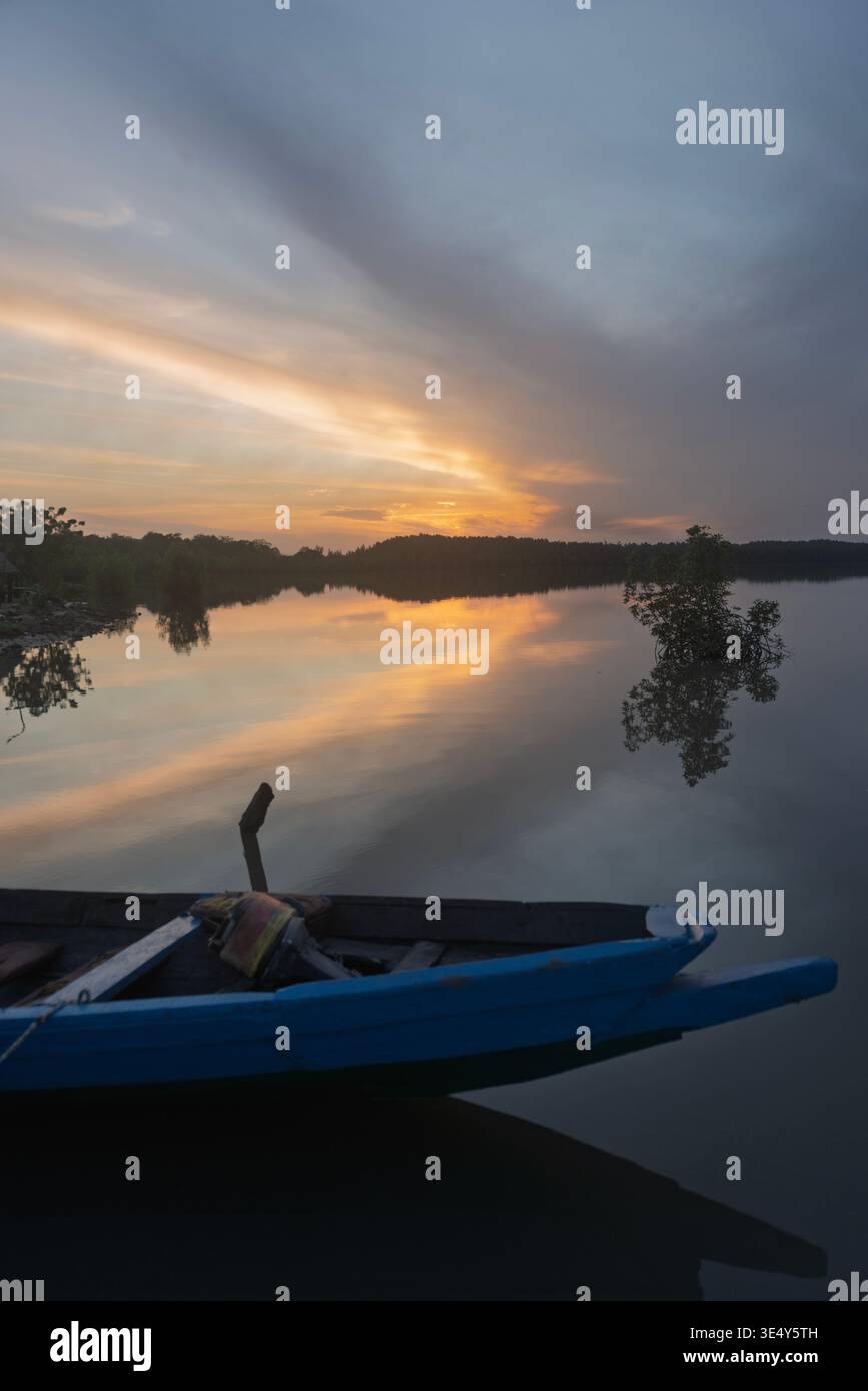 Sunset view of a blue colored wooden canoe at a crumbled jetty in the Gambia river. Tendaba, The Gambia. Stock Photo