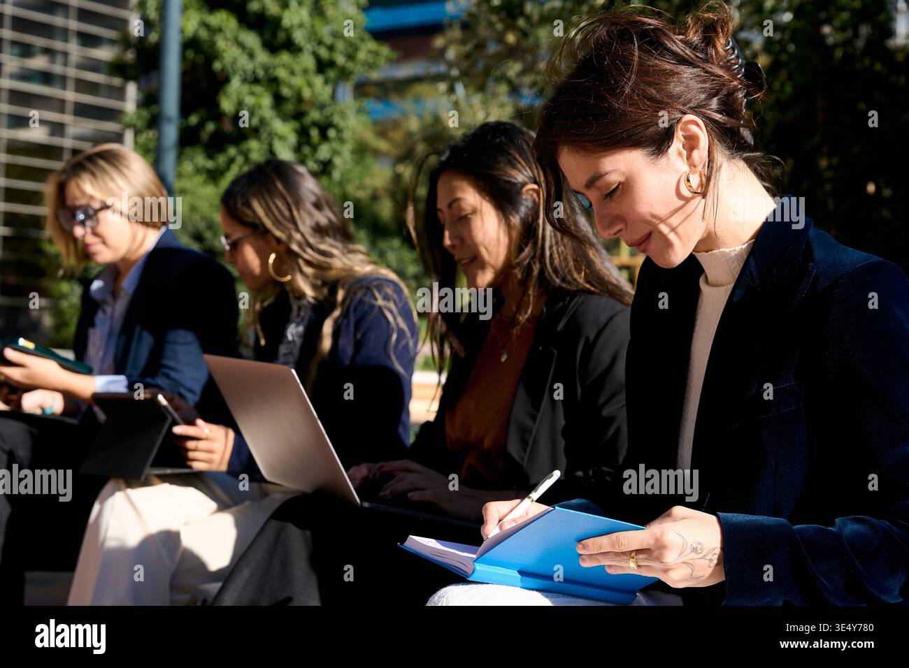 Businesswomen collaborating outdoors using modern technology Stock Photo