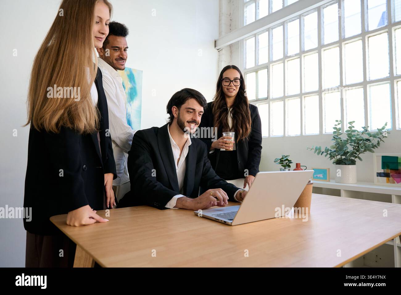 Diverse business team collaborating using laptop in office Stock Photo