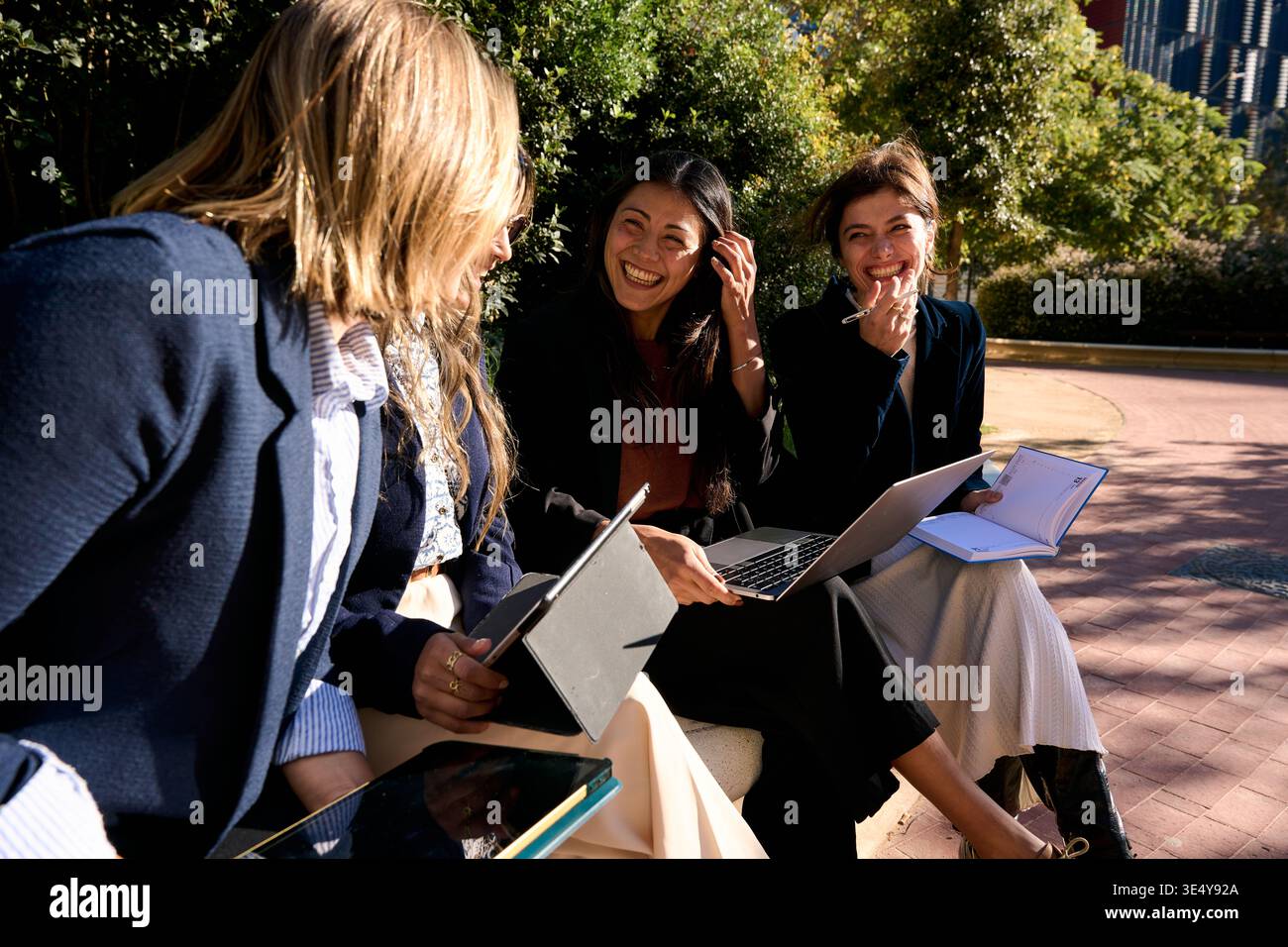 Businesswomen collaborating outdoors using laptops and tablets Stock Photo